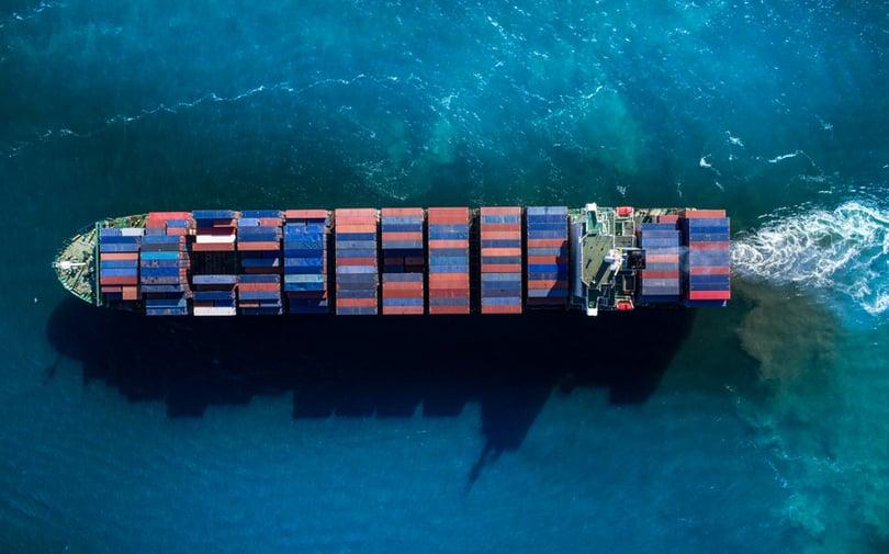 A large blue container ship carrying multi-colored freight across the ocean.